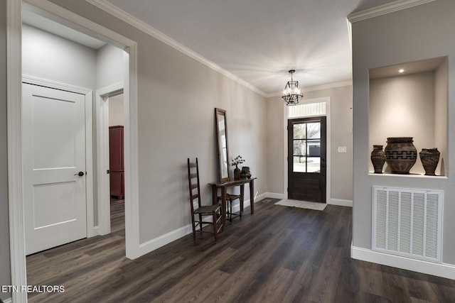 foyer entrance with dark wood-type flooring, ornamental molding, and a chandelier