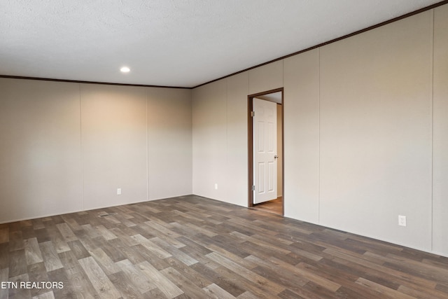 spare room featuring crown molding, dark wood-type flooring, and a textured ceiling