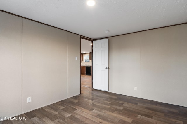 spare room featuring dark wood-type flooring and a textured ceiling