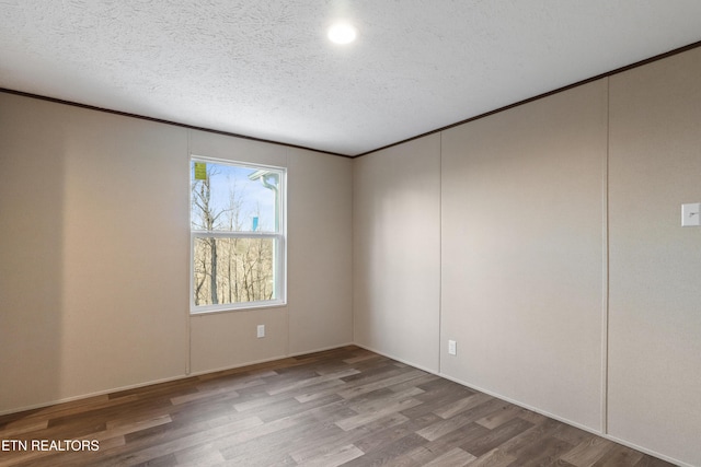 spare room featuring hardwood / wood-style flooring and a textured ceiling