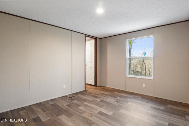 unfurnished room featuring hardwood / wood-style flooring and a textured ceiling