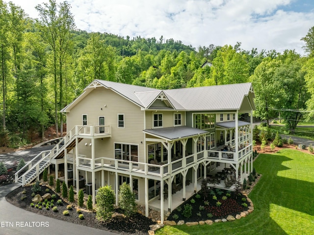 rear view of property featuring a wooden deck, a balcony, and a lawn