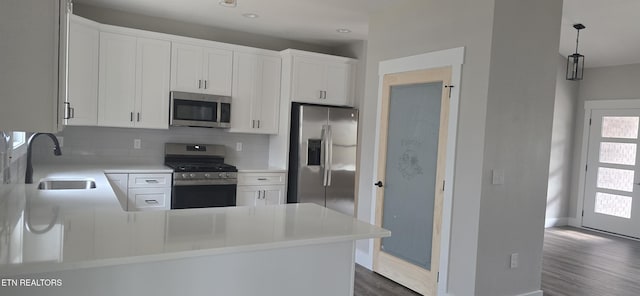 kitchen with light countertops, a sink, tasteful backsplash, appliances with stainless steel finishes, and dark wood-style floors