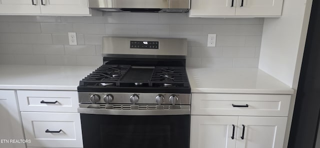 kitchen with light countertops, stainless steel gas range oven, tasteful backsplash, and white cabinetry