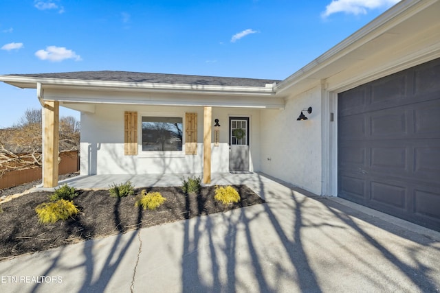 view of exterior entry with a garage and a porch