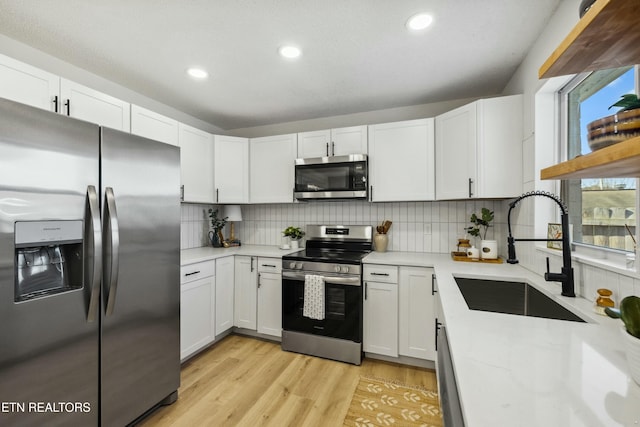 kitchen featuring stainless steel appliances, white cabinetry, sink, and light wood-type flooring