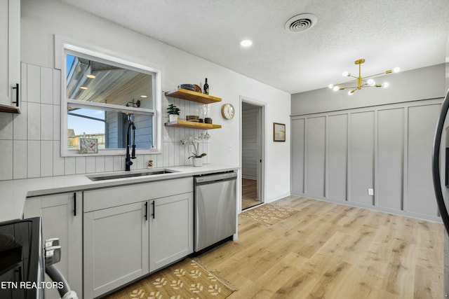 kitchen featuring sink, tasteful backsplash, a textured ceiling, light wood-type flooring, and dishwasher