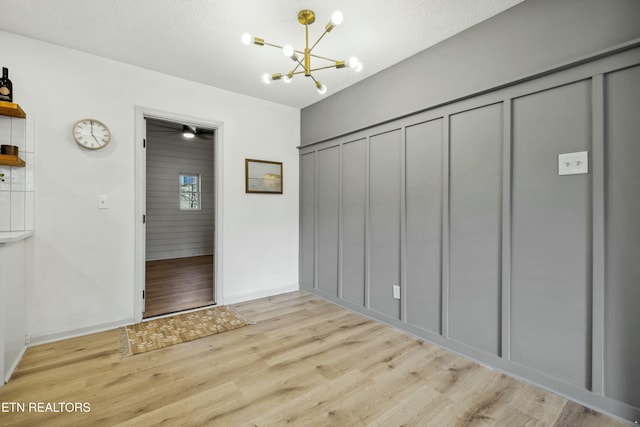 interior space with a chandelier, a textured ceiling, and light wood-type flooring