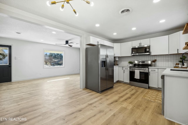 kitchen with sink, white cabinetry, light hardwood / wood-style flooring, appliances with stainless steel finishes, and decorative backsplash