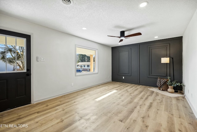 foyer featuring ceiling fan, a textured ceiling, and light wood-type flooring