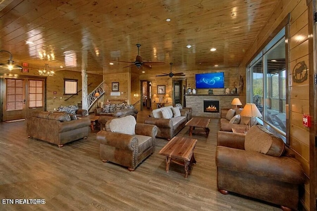 living room featuring wood walls, wood-type flooring, a stone fireplace, and wooden ceiling