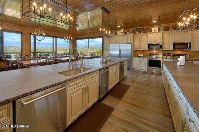 kitchen with sink, hanging light fixtures, wooden ceiling, appliances with stainless steel finishes, and light stone countertops