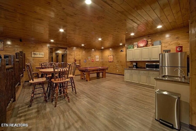 dining area with wood ceiling, wooden walls, sink, and light hardwood / wood-style flooring