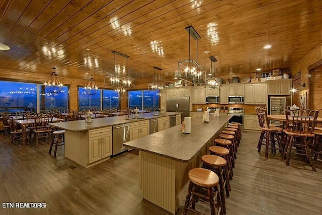 kitchen featuring appliances with stainless steel finishes, a breakfast bar, pendant lighting, a large island, and dark wood-type flooring