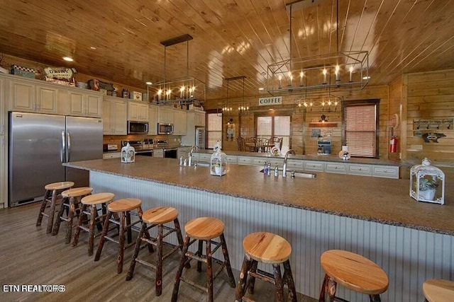 kitchen with a kitchen bar, sink, wood ceiling, decorative light fixtures, and appliances with stainless steel finishes