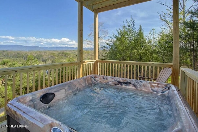 wooden terrace featuring a hot tub and a mountain view