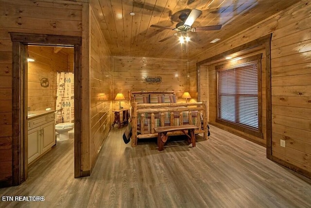 bedroom with wood ceiling, light hardwood / wood-style flooring, ensuite bath, and wood walls