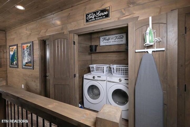 laundry area with wooden walls, wood ceiling, and washer and clothes dryer