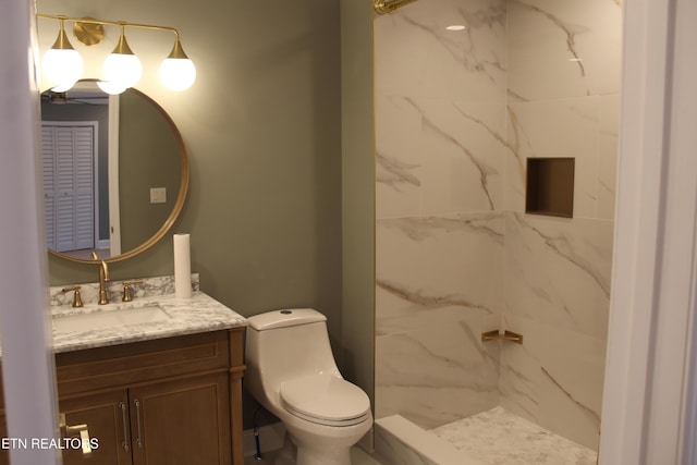 bathroom with vanity, tiled shower, and toilet