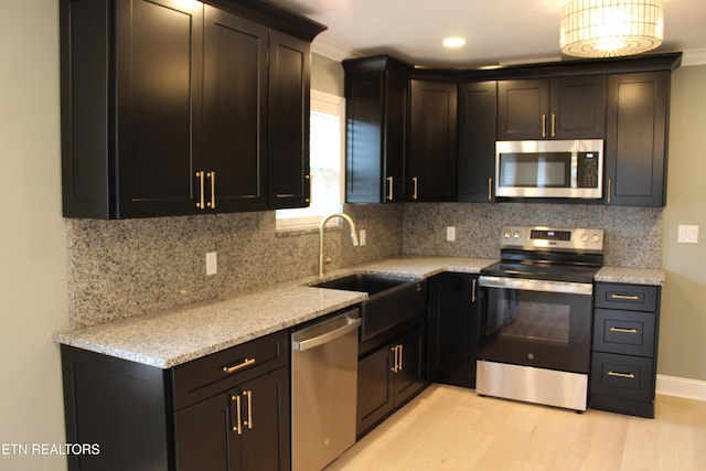 kitchen featuring appliances with stainless steel finishes, sink, backsplash, and light stone counters