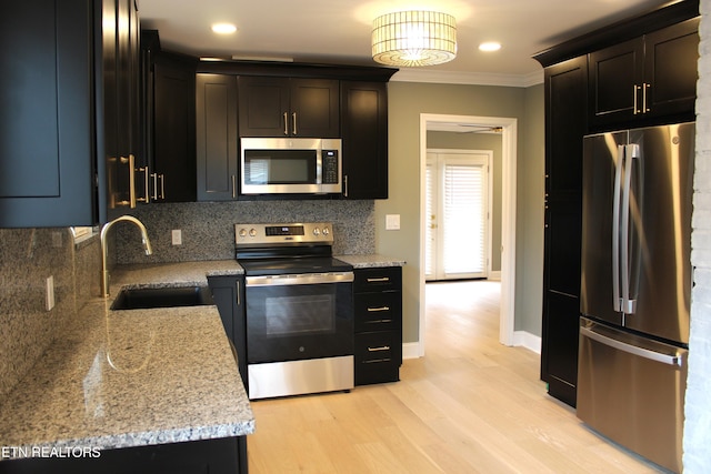 kitchen with sink, appliances with stainless steel finishes, backsplash, light stone countertops, and light wood-type flooring