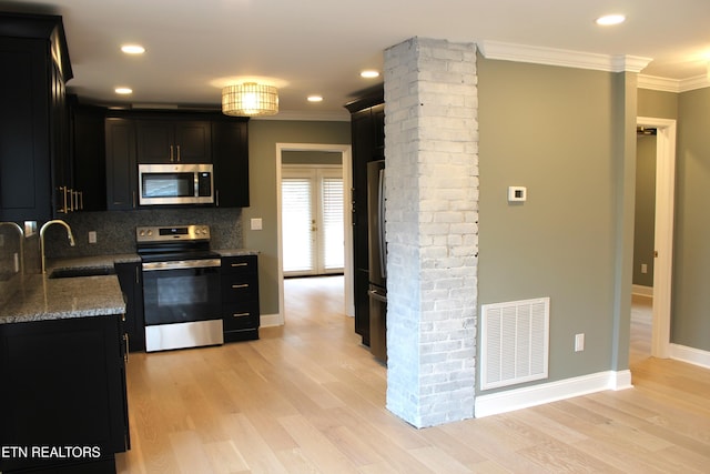 kitchen featuring tasteful backsplash, light stone counters, ornamental molding, stainless steel appliances, and light hardwood / wood-style floors