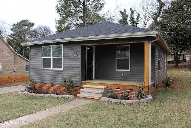 bungalow-style house with a shingled roof and a front lawn