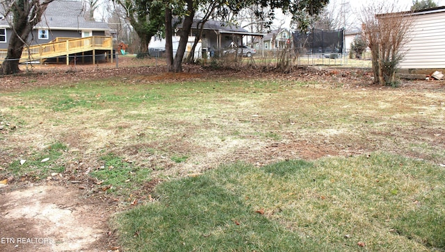 view of yard featuring a deck and a trampoline