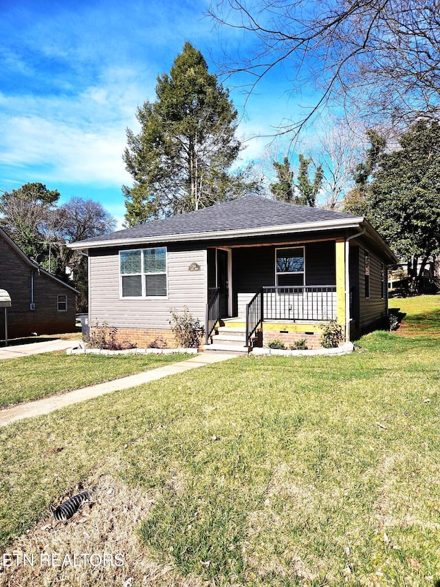 ranch-style house with covered porch, roof with shingles, and a front yard