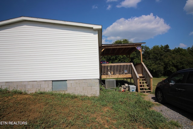 view of home's exterior featuring cooling unit, a deck, and a lawn