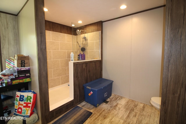 bathroom featuring hardwood / wood-style flooring, a tile shower, and toilet