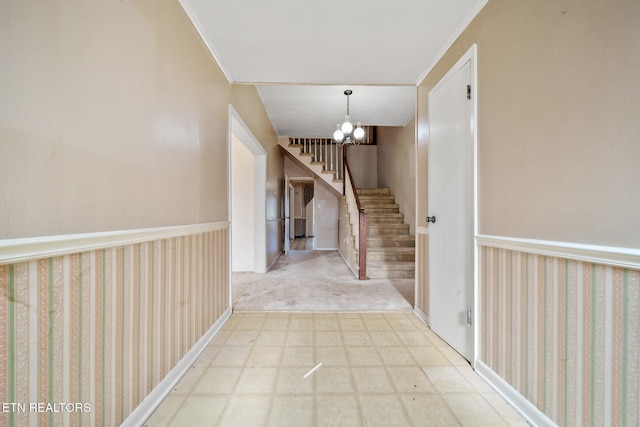 hall featuring tile patterned floors, wainscoting, a notable chandelier, and stairs