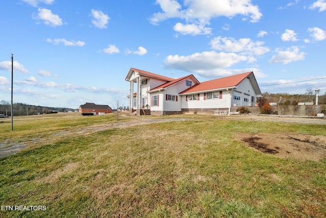 view of side of property with metal roof and a yard