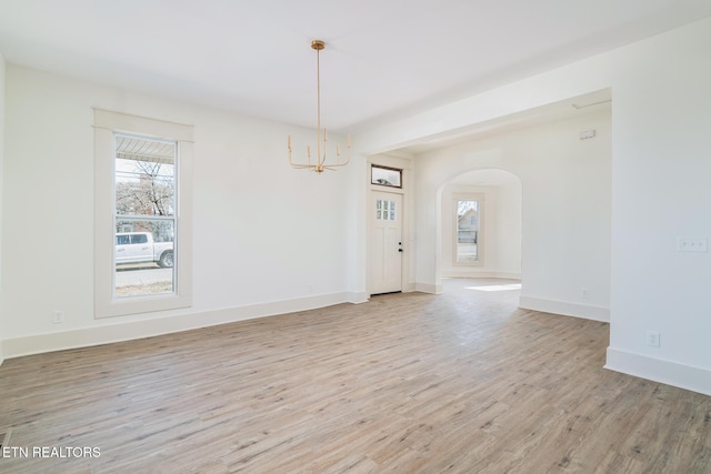 unfurnished room with an inviting chandelier and light hardwood / wood-style flooring