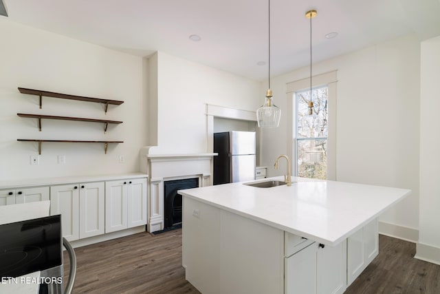 kitchen with pendant lighting, sink, stainless steel fridge, an island with sink, and white cabinets