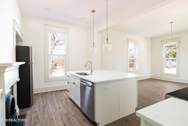 kitchen with sink, decorative light fixtures, appliances with stainless steel finishes, a kitchen island with sink, and white cabinets