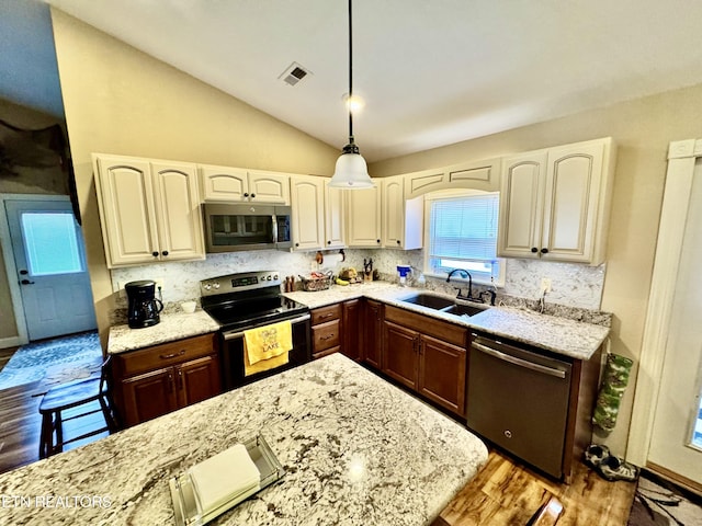 kitchen featuring dark brown cabinetry, sink, hanging light fixtures, appliances with stainless steel finishes, and decorative backsplash