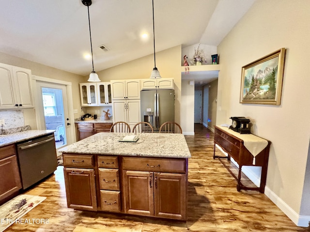 kitchen with light hardwood / wood-style flooring, appliances with stainless steel finishes, white cabinetry, a center island, and vaulted ceiling