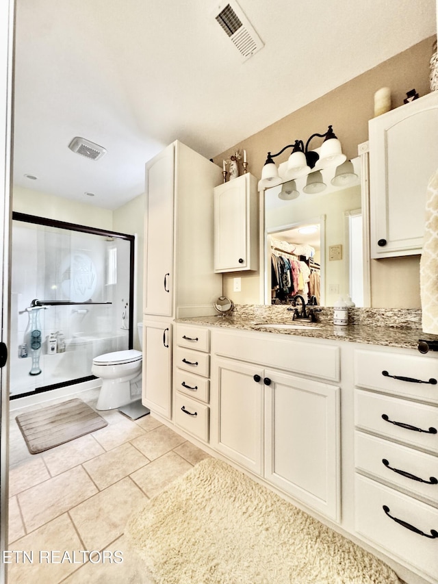 bathroom with vanity, toilet, tile patterned floors, and a shower with shower door