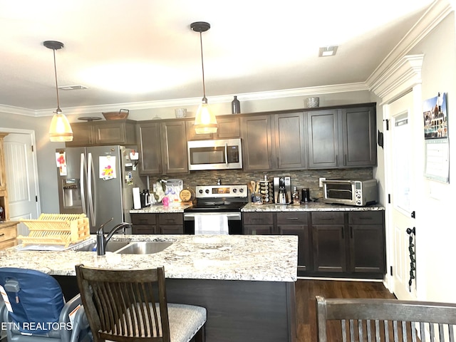 kitchen with appliances with stainless steel finishes, sink, pendant lighting, and dark brown cabinets