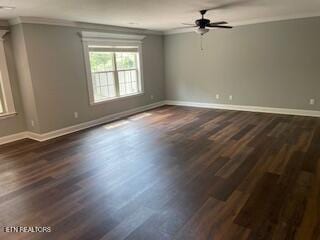 empty room featuring dark wood-type flooring, ceiling fan, crown molding, and baseboards