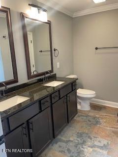 full bath with double vanity, toilet, crown molding, and a sink