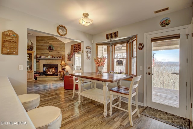 dining space featuring hardwood / wood-style flooring, a wealth of natural light, and a multi sided fireplace