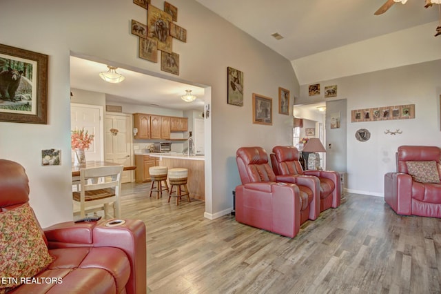 living room with vaulted ceiling, sink, ceiling fan, and light hardwood / wood-style floors