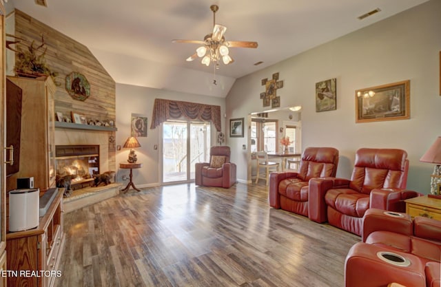 living room featuring ceiling fan, a large fireplace, wood-type flooring, and vaulted ceiling