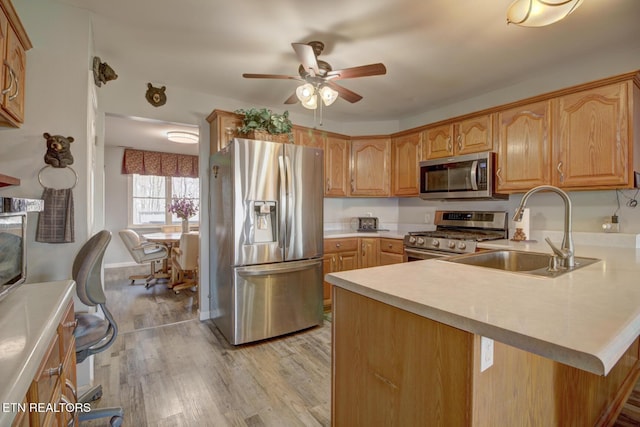 kitchen featuring sink, light hardwood / wood-style flooring, ceiling fan, appliances with stainless steel finishes, and kitchen peninsula