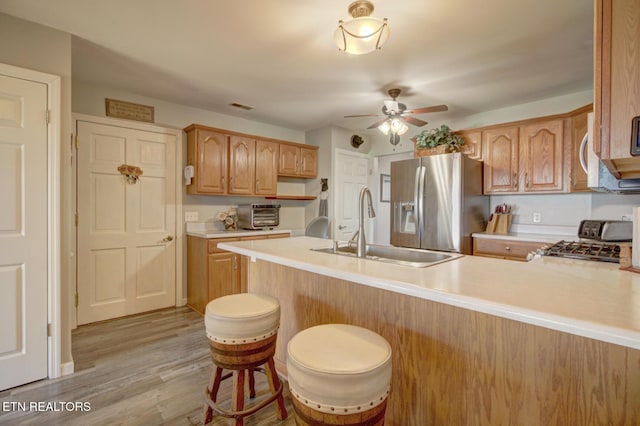 kitchen with sink, a breakfast bar area, range, kitchen peninsula, and light hardwood / wood-style floors