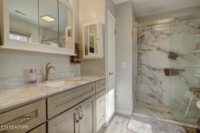 bathroom with hardwood / wood-style flooring, vanity, and an enclosed shower