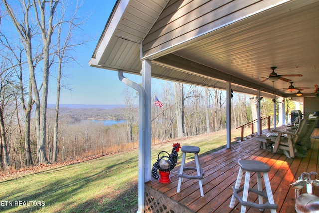 wooden deck featuring a water view, ceiling fan, and a yard