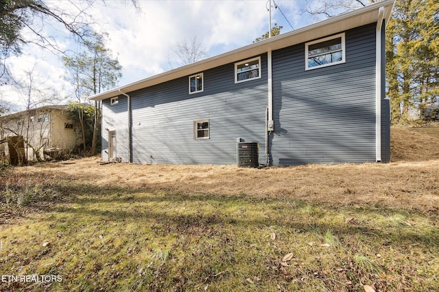 view of home's exterior with cooling unit and a yard